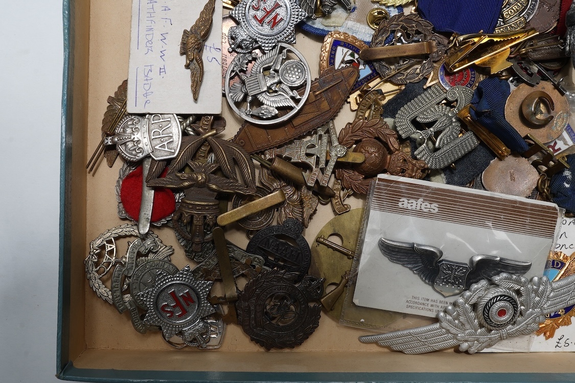 A collection of primarily 20th century military badges, lapel badges, shoulder titles, and other related ephemera, including seventeen military cap badges, cloth badges, ARP badges, etc., together with a military tin box